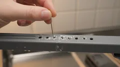 Persona fora metallo con trapano a mano, dettagli fai da te su superficie di acciaio.